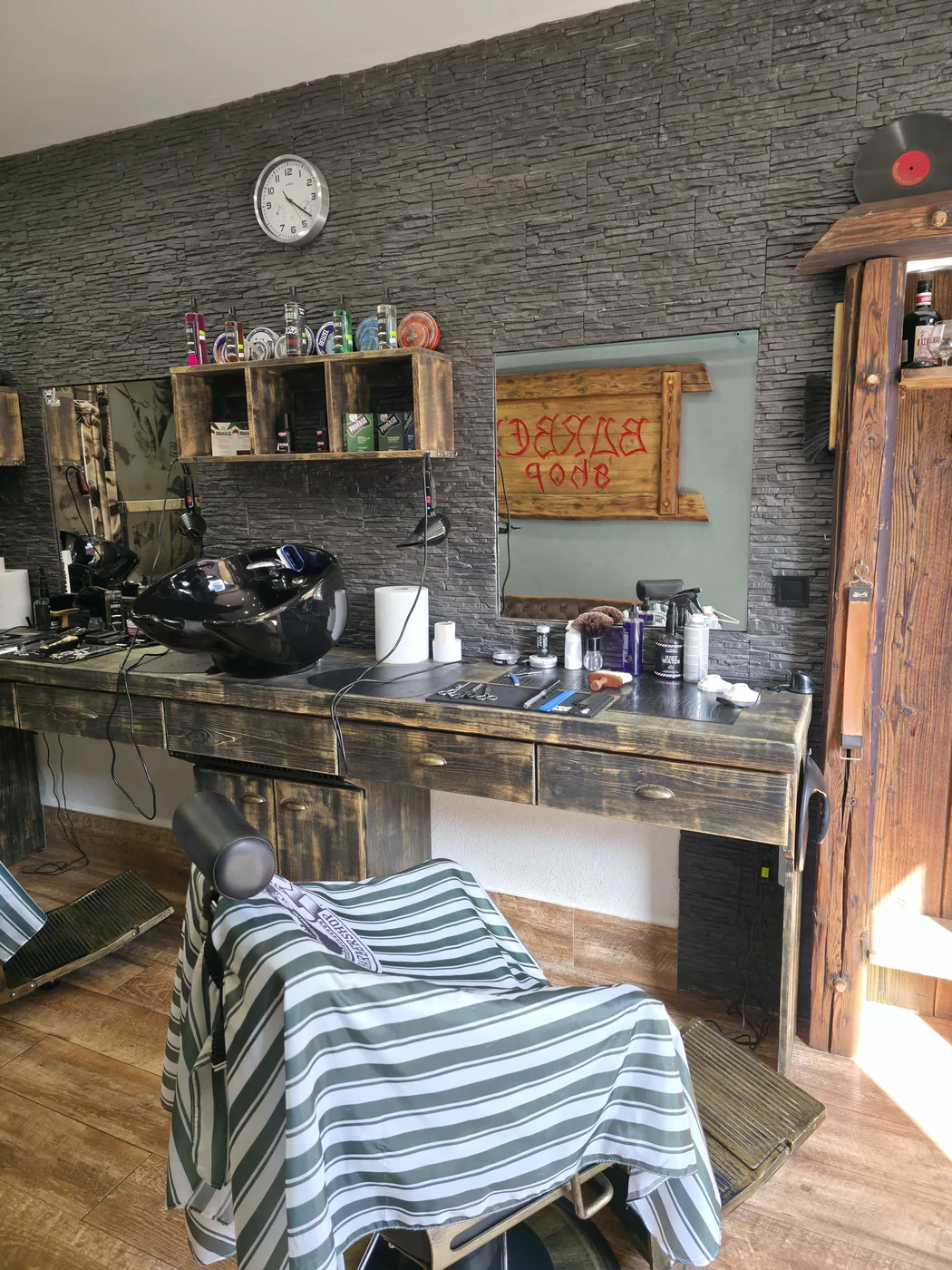 Umývací box, drevený pult a produkty pri kamennej stene v Barber Shop MF
