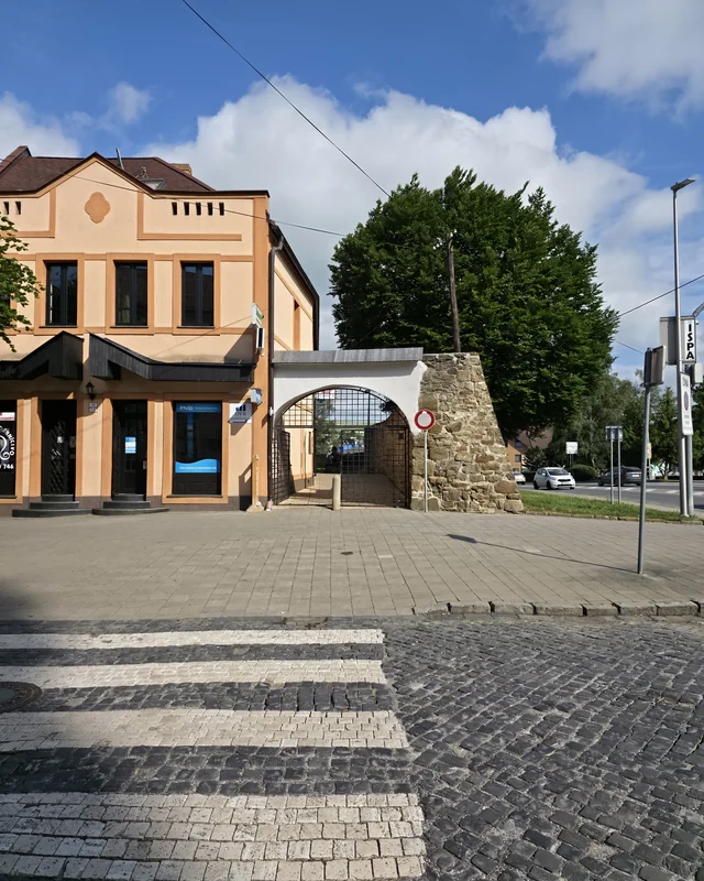 Barber Shop MF od priechodu pre chodcov — nárožná budova s bránou v centre Kežmarku